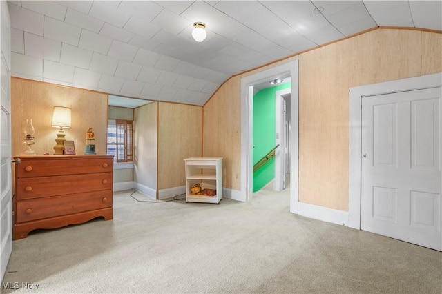 bedroom featuring baseboards, vaulted ceiling, wood walls, and carpet