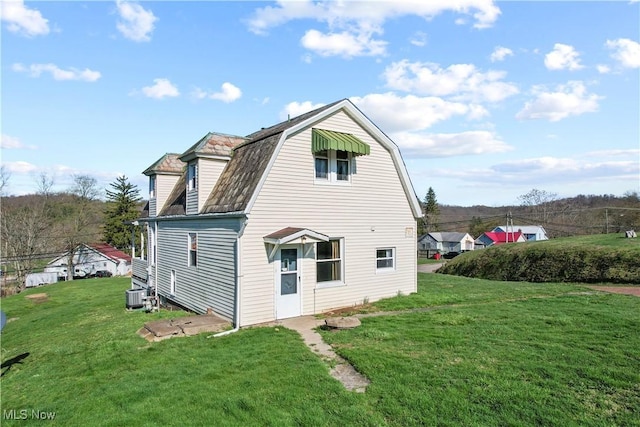 rear view of house featuring a lawn, central AC unit, and a gambrel roof