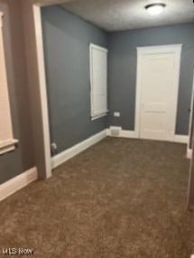 spare room with dark carpet and baseboards