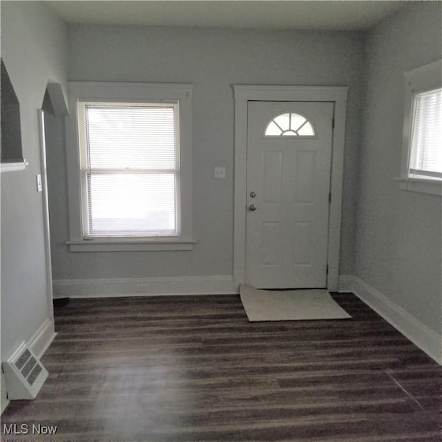entryway with dark wood-type flooring, visible vents, and baseboards