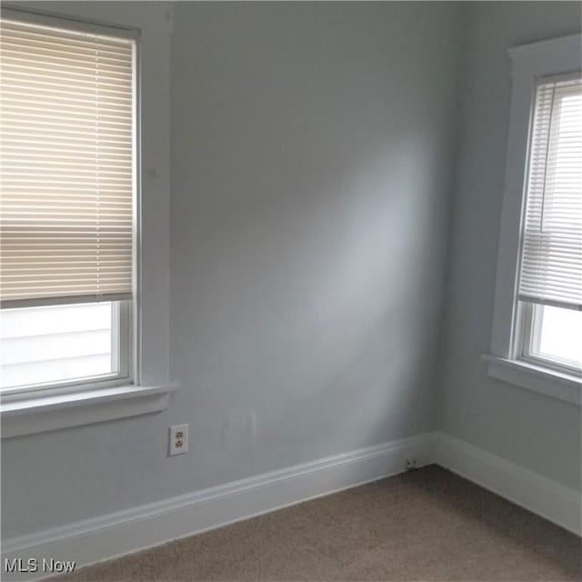 spare room with baseboards and carpet floors