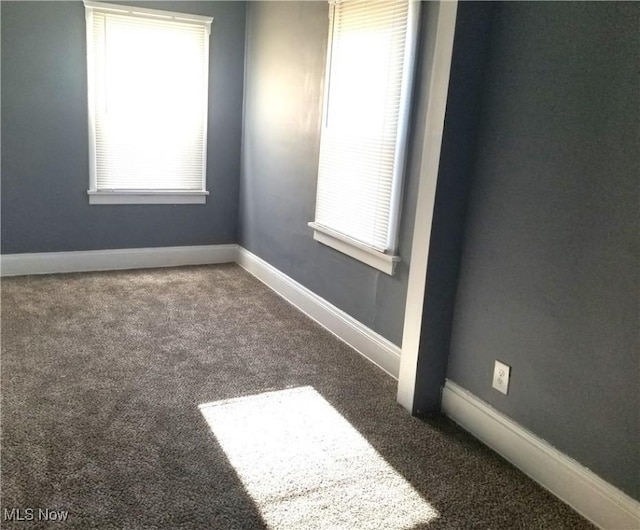 empty room featuring a wealth of natural light, carpet flooring, and baseboards
