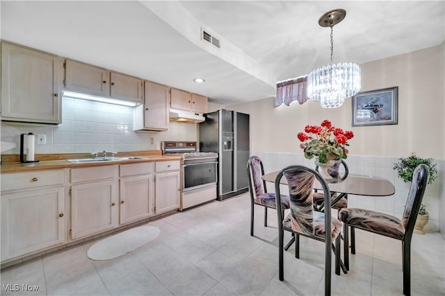 6722 Silvermound Dr, Mentor, OH 44060 - kitchen with range, stainless steel refrigerator with ice dispenser, a chandelier, under cabinet range hood, and decorative light fixtures