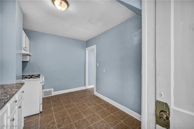 washroom featuring baseboards, visible vents, and dark tile patterned floors