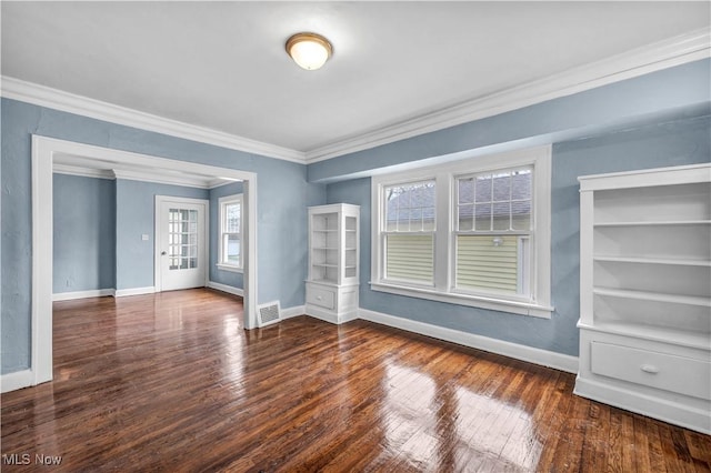 empty room with baseboards, visible vents, ornamental molding, and wood-type flooring