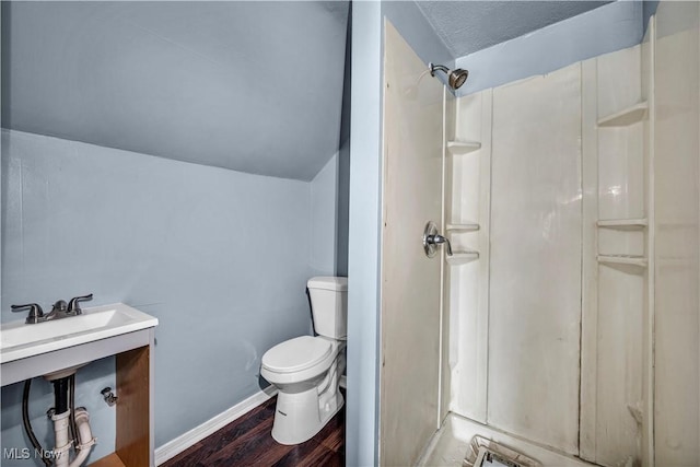 full bathroom with toilet, a shower, wood finished floors, lofted ceiling, and baseboards