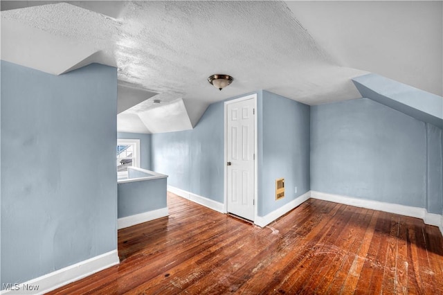 additional living space with wood-type flooring, baseboards, and vaulted ceiling