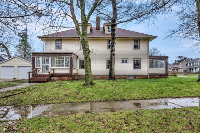 exterior space with a sunroom, a chimney, a garage, a lawn, and an outbuilding