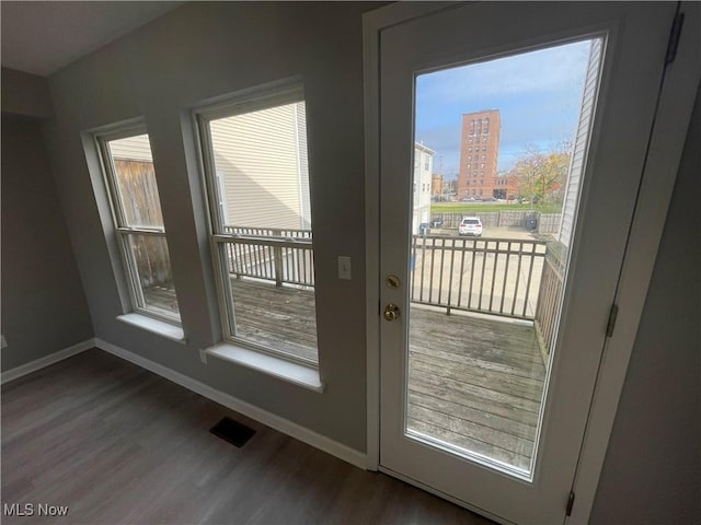 doorway featuring a view of city, visible vents, baseboards, and wood finished floors