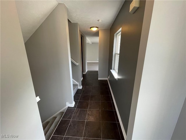 hall with a textured ceiling, baseboards, tile patterned flooring, and stairway