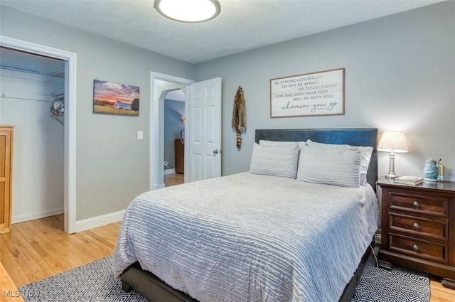 bedroom featuring baseboards, wood finished floors, and a closet