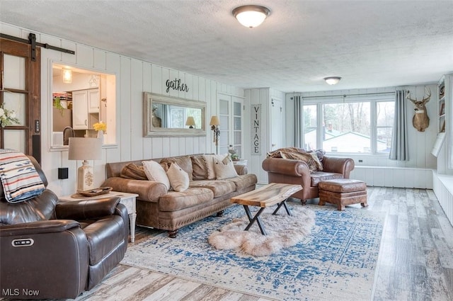 living room featuring a textured ceiling, a barn door, and wood finished floors