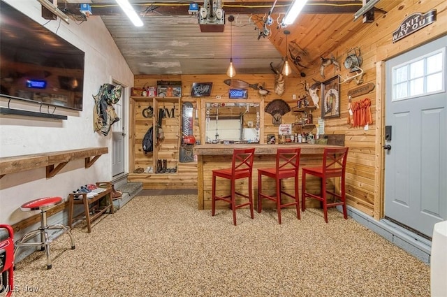 dining space with a workshop area, wood ceiling, and wood walls