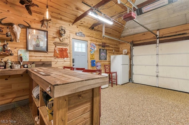 garage featuring wood walls, a garage door opener, and freestanding refrigerator