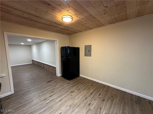 unfurnished room with electric panel, baseboards, and wood finished floors