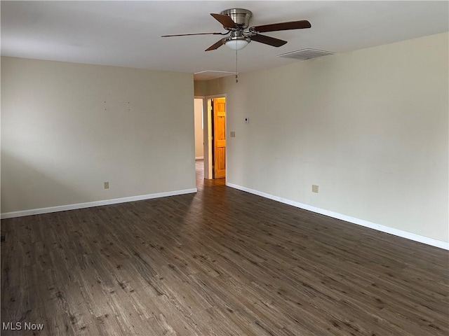 empty room featuring attic access, dark wood-type flooring, baseboards, visible vents, and a ceiling fan