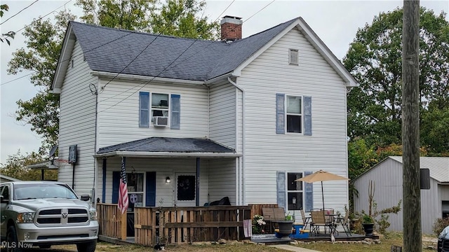 view of front of house with a porch, cooling unit, a chimney, and a shingled roof
