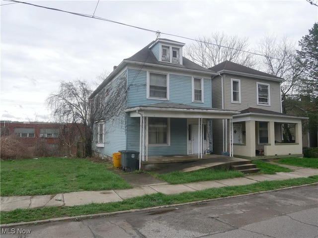 american foursquare style home featuring a porch and a front lawn