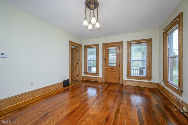 entrance foyer featuring baseboards, hardwood / wood-style flooring, and an inviting chandelier