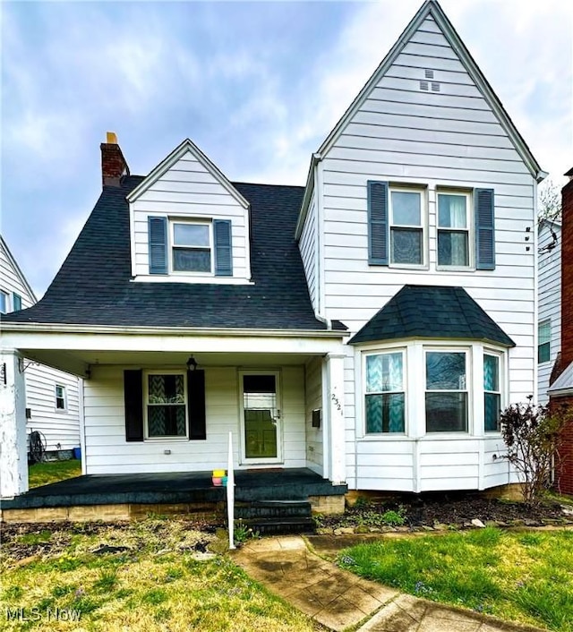 view of front of home with covered porch, a shingled roof, and a chimney