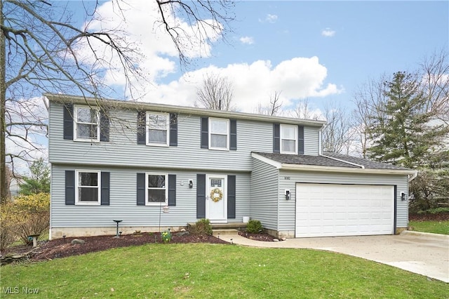 colonial home featuring a front yard, concrete driveway, and a garage