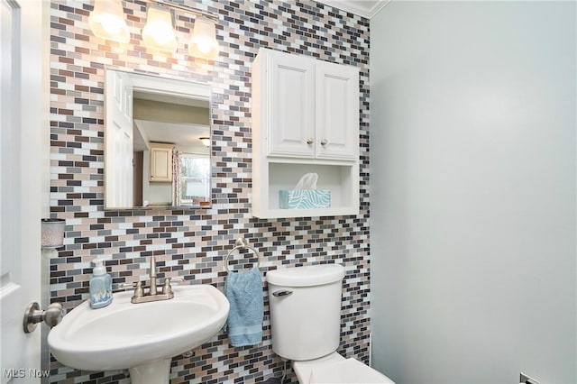 half bathroom with tasteful backsplash, toilet, and a sink