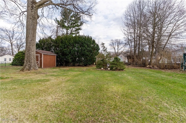 view of yard featuring fence, a storage unit, and an outbuilding