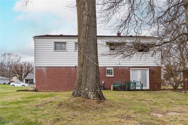rear view of house featuring a yard and brick siding