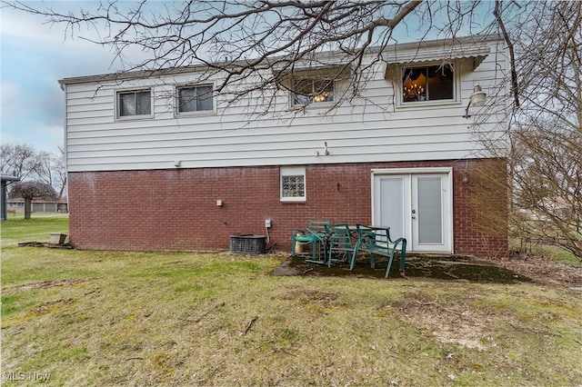 rear view of house featuring a yard, brick siding, and central air condition unit