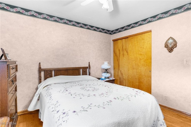 bedroom with baseboards, ceiling fan, a closet, and wood finished floors