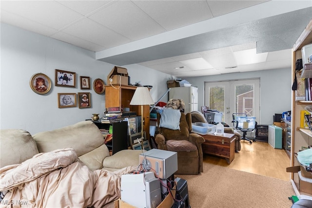 living room featuring french doors, light wood finished floors, and a paneled ceiling