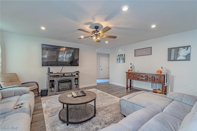 living room with baseboards, a ceiling fan, recessed lighting, wood finished floors, and a glass covered fireplace