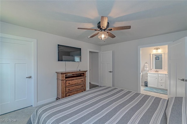 bedroom featuring ensuite bathroom, baseboards, a sink, a ceiling fan, and light colored carpet