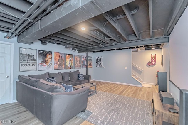 living area featuring baseboards, wood finished floors, and stairs