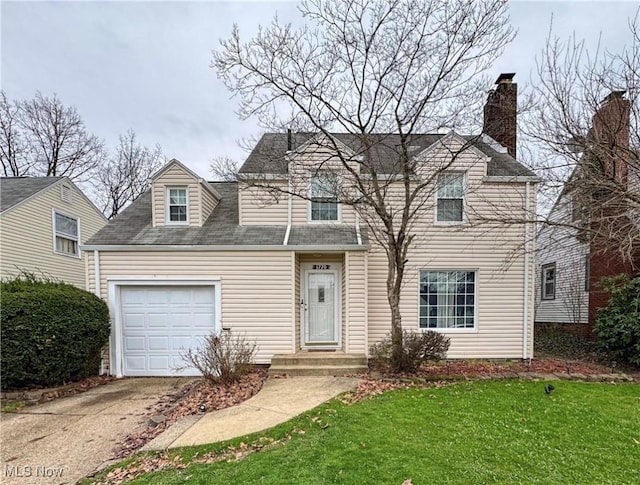 view of front of home featuring a front yard, an attached garage, a chimney, a shingled roof, and driveway