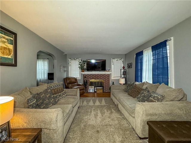 living area featuring arched walkways and a fireplace