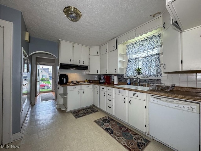 kitchen with open shelves, dark countertops, under cabinet range hood, white dishwasher, and a sink