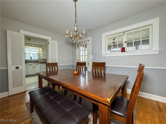 dining area with a notable chandelier, baseboards, and wood finished floors
