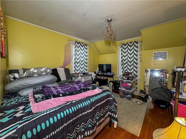 bedroom with wood finished floors, ornamental molding, and lofted ceiling
