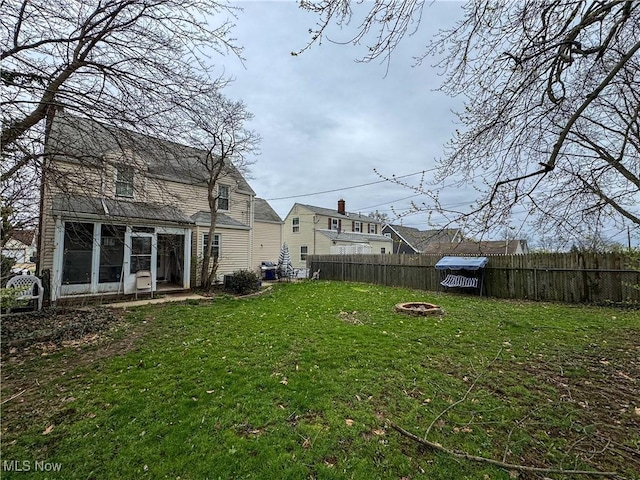 view of yard featuring an outdoor fire pit, fence, and a sunroom
