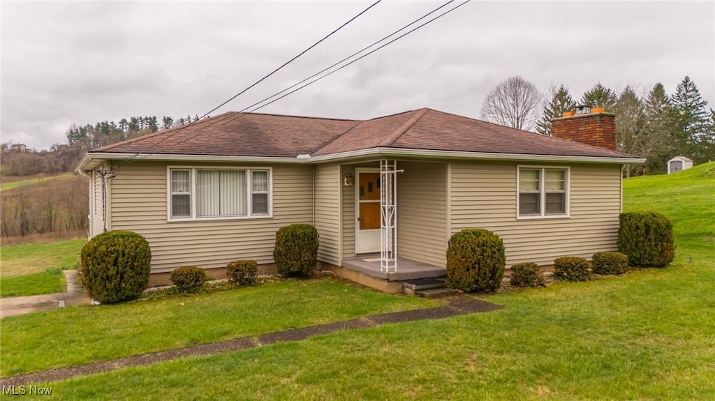 54260 Bracken Rd, Bridgeport, OH 43912 - view of front of home with a chimney, a shingled roof, and a front lawn