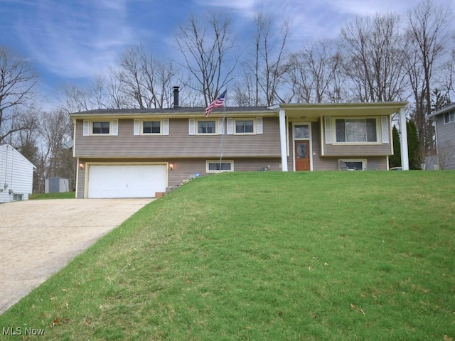 raised ranch with driveway, a garage, and a front lawn