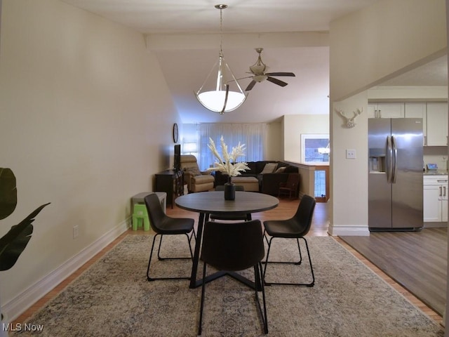 dining space with ceiling fan, vaulted ceiling, wood finished floors, and baseboards