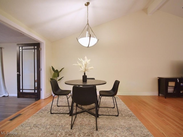 dining room featuring visible vents, baseboards, vaulted ceiling with beams, and wood finished floors