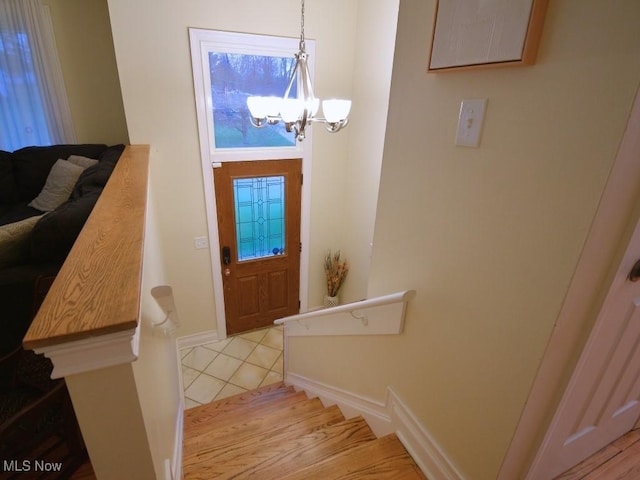 foyer featuring a chandelier, stairway, baseboards, and light tile patterned floors