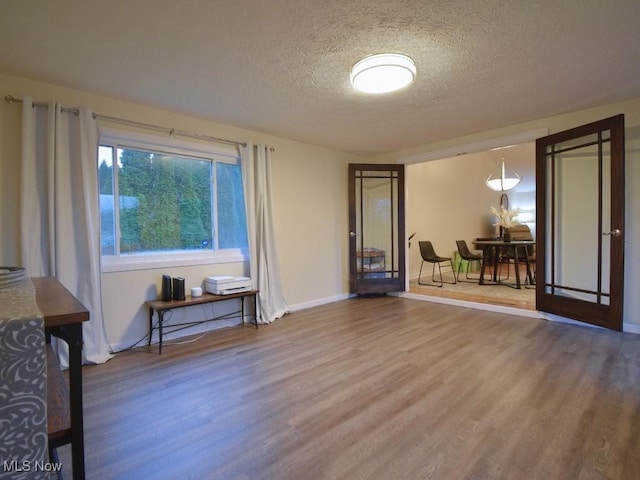 interior space featuring a textured ceiling, baseboards, and wood finished floors