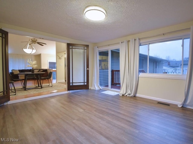 spare room featuring visible vents, baseboards, wood finished floors, and a textured ceiling