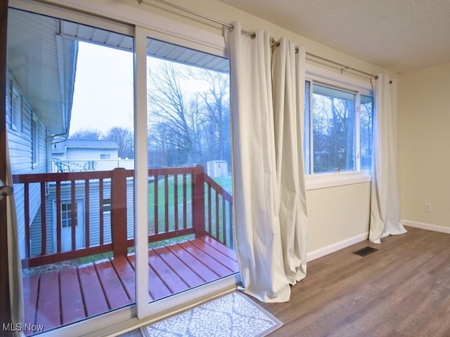 doorway to outside with visible vents, baseboards, and wood finished floors