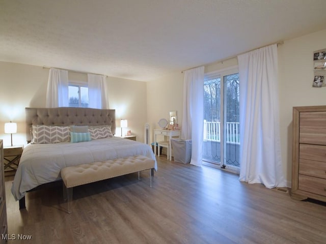 bedroom with access to exterior and wood finished floors