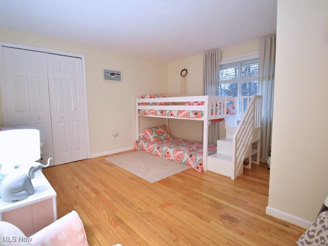 bedroom with wood finished floors, a closet, and baseboards